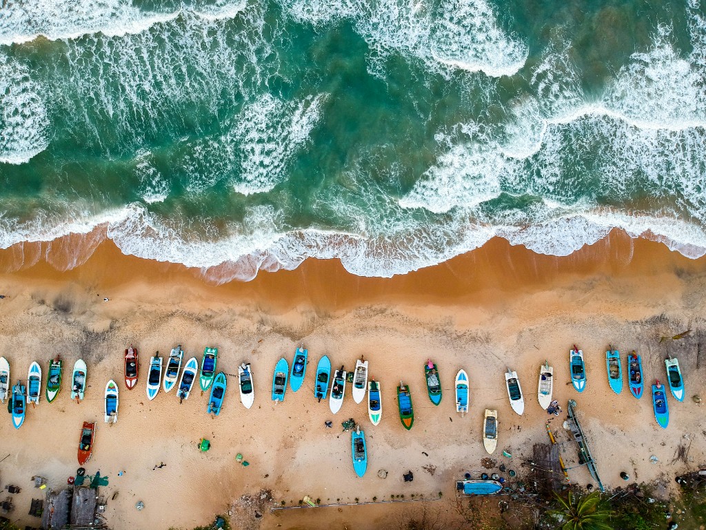 Aerial view of Arugam Bay beach with colorful fishing boats in Sri Lanka